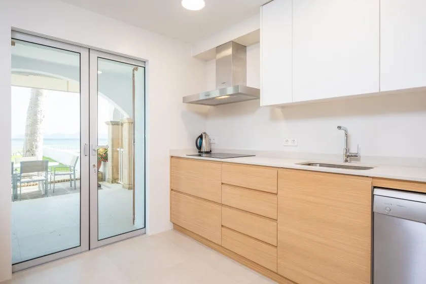 A bright kitchen with light wood cabinets and sliding glass doors opening onto a patio.