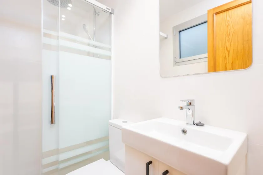 A bright bathroom with a glass shower and a sink.