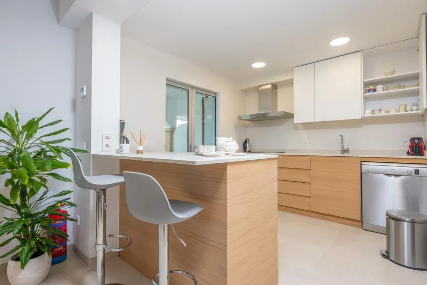 A bright modern kitchen with a wood-fronted island and open shelving.
