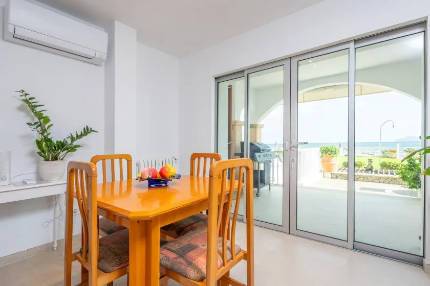 A dining area with a wooden table and chairs beside glass doors.
