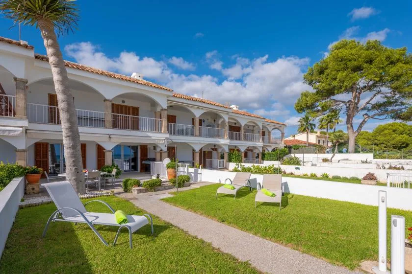 A sunny courtyard with lawn seating in front of a row of white buildings.