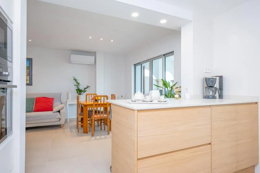 A bright open-plan kitchen and dining area with a wooden island and dining table.