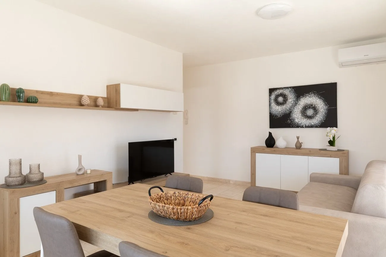 Una luminosa sala de estar y comedor con una mesa de madera y un televisor.