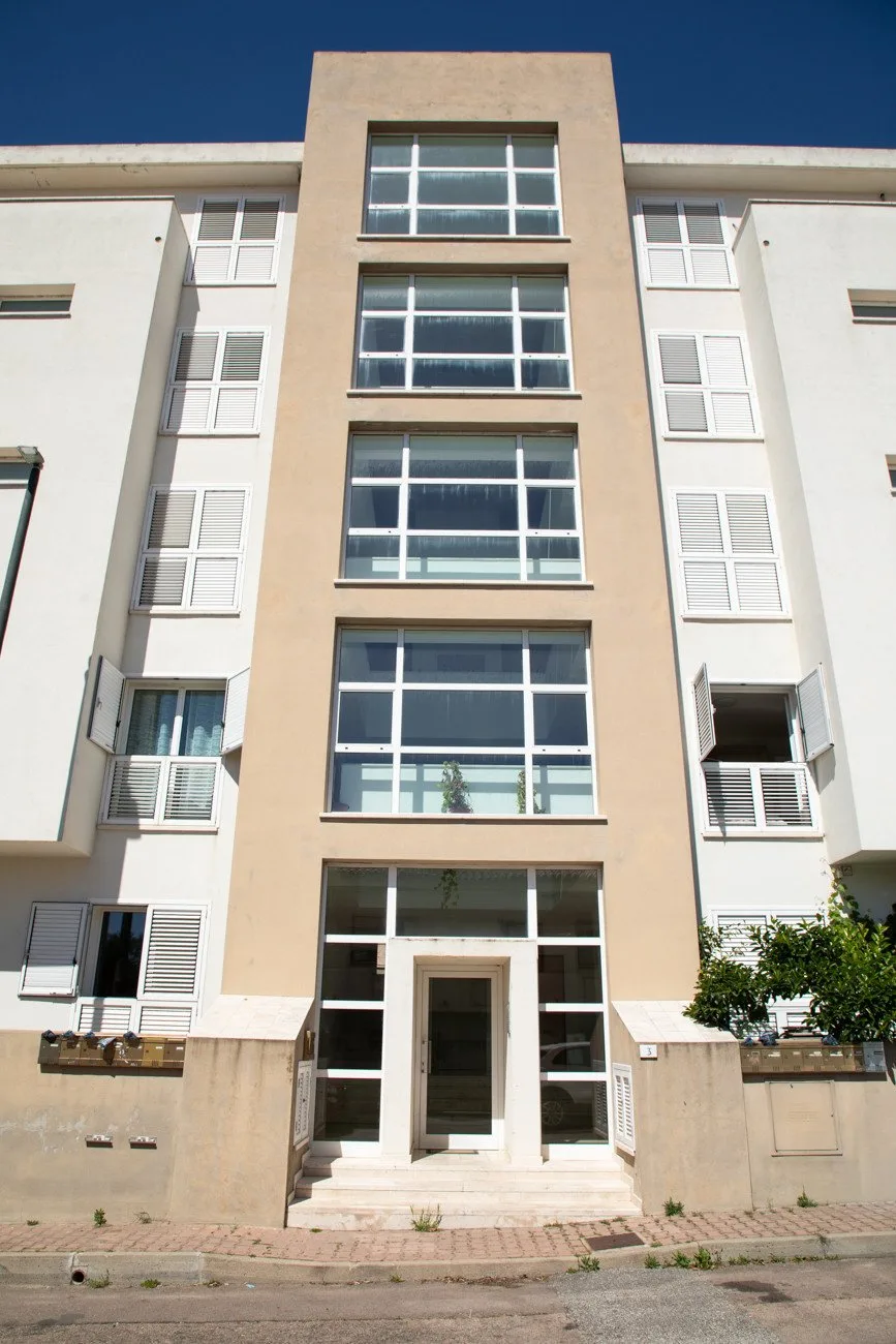 Fachada de un edificio de varias plantas con entrada central y filas de ventanas.