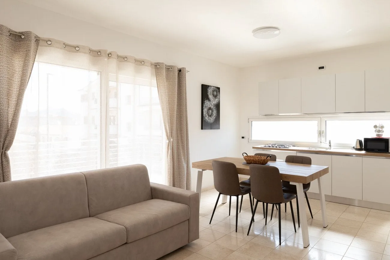 Una luminosa sala de estar y comedor con un sofá junto a una mesa y cocina.