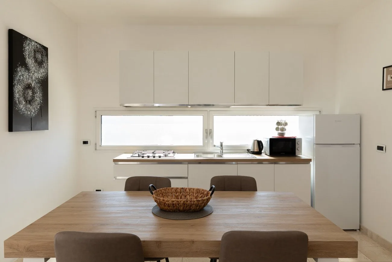 Una cocina luminosa con comedor y una mesa de madera en primer plano.
