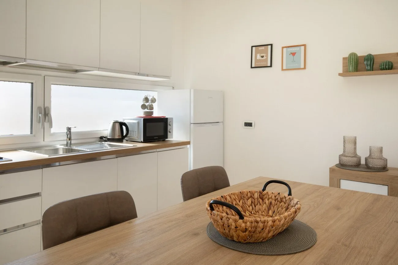 Un comedor con una mesa de madera junto a una cocina compacta.