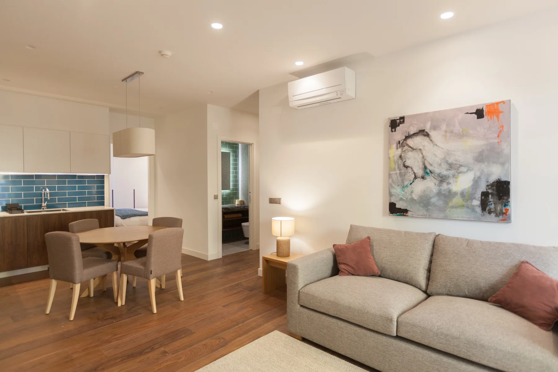 A living room and dining area with seating, a table, and wall art.