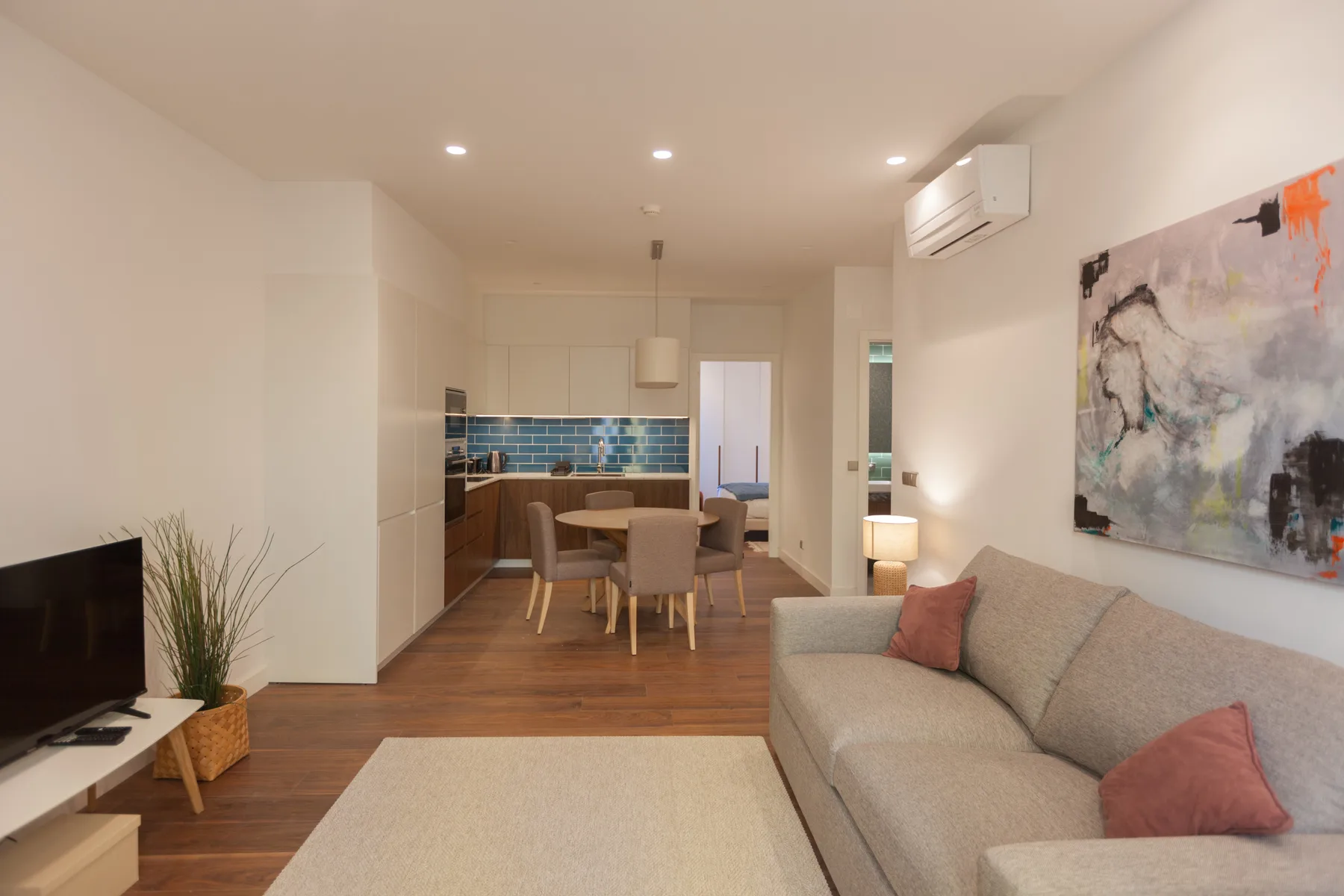 Living room with seating, a dining table, and an open kitchen.