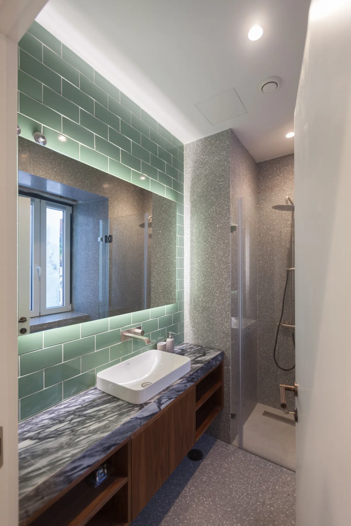 A modern bathroom with a sink, large mirror, and shower.