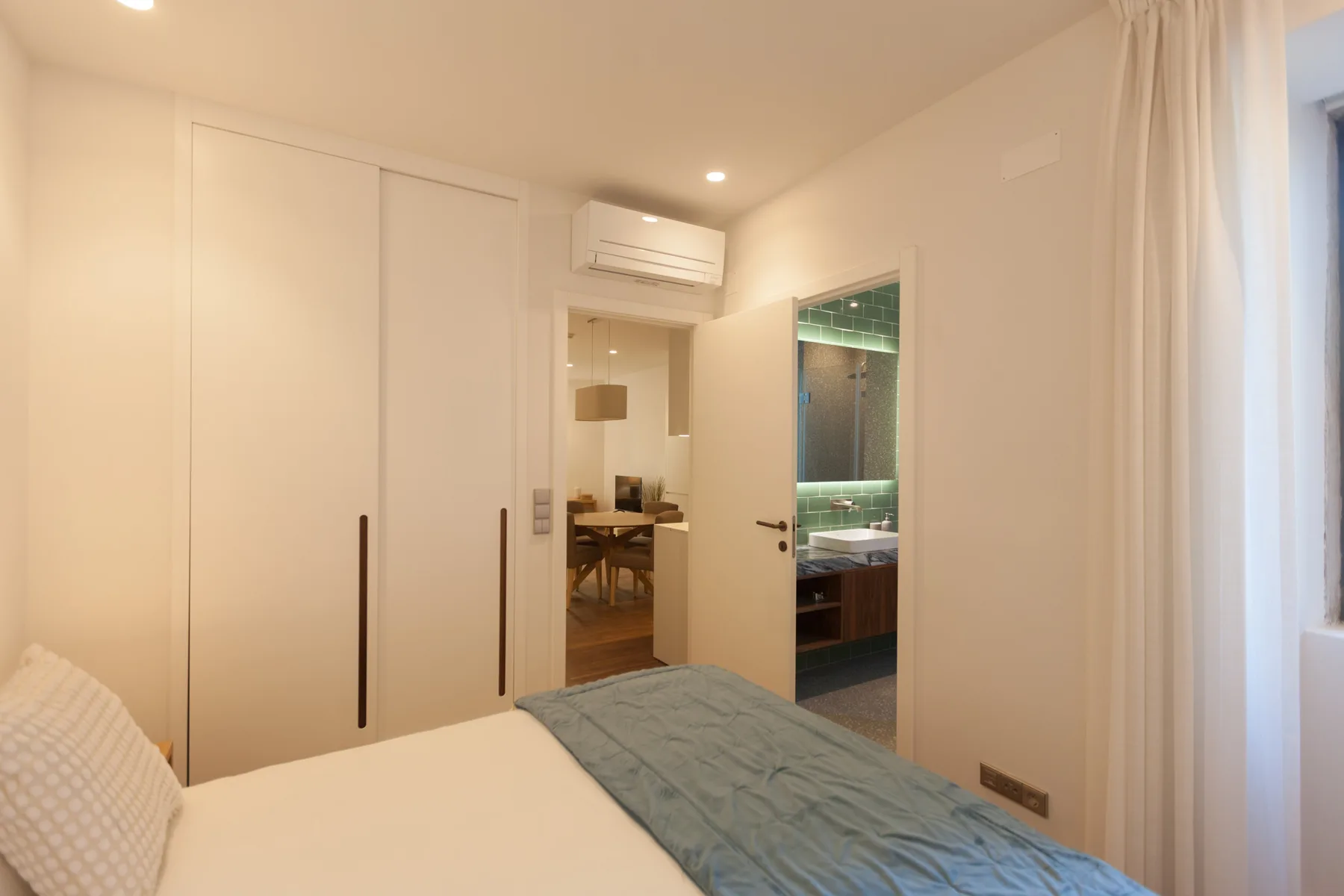 A bedroom with a bed and an open doorway leading to a bathroom.