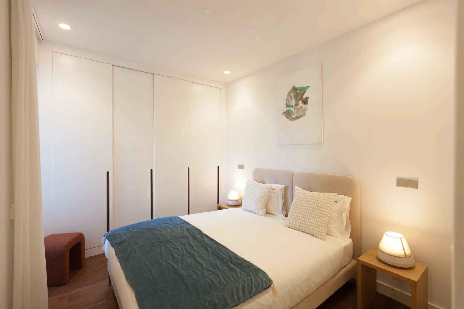 A bright bedroom with a double bed and built-in wardrobes.