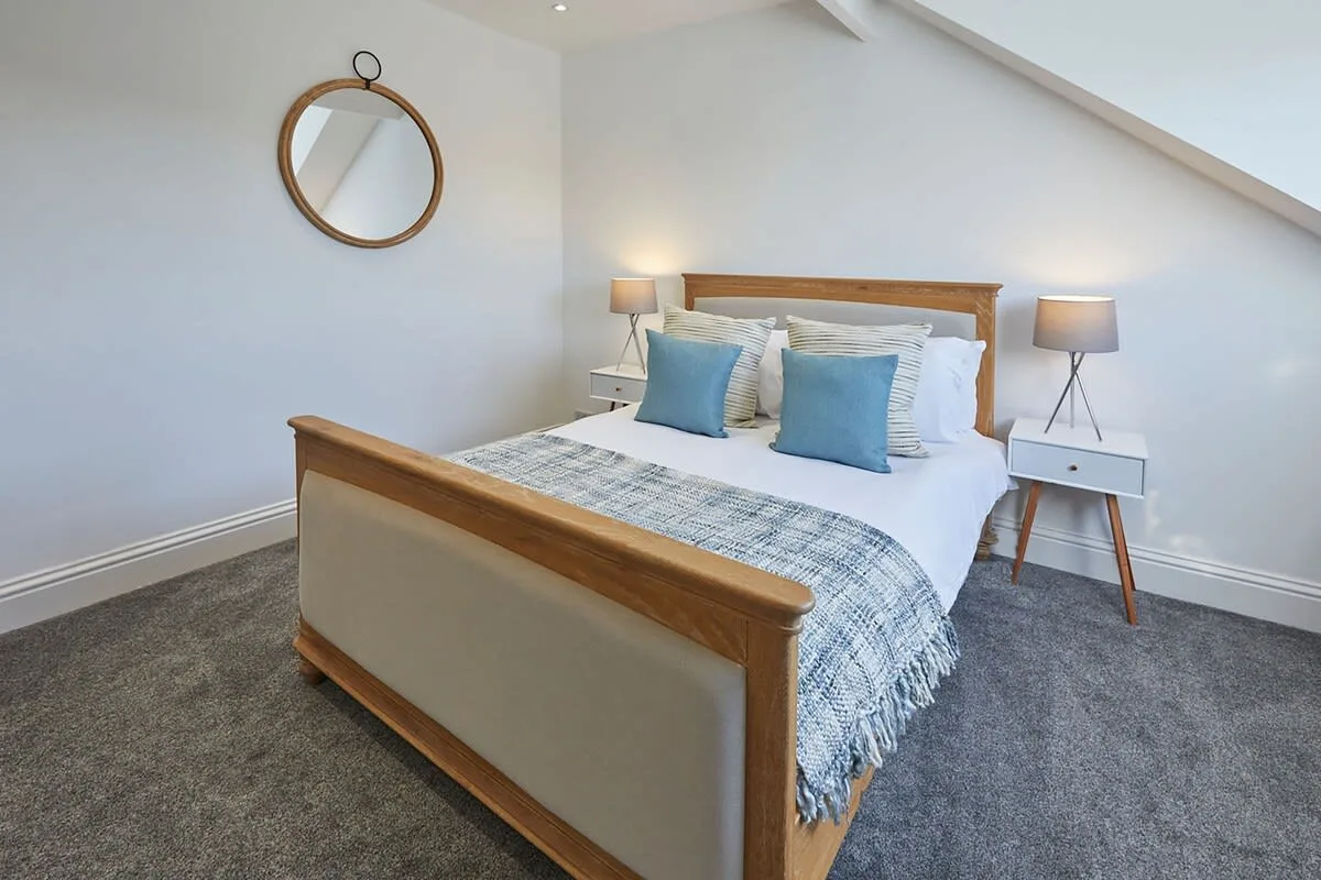 A bedroom with a wooden bed, blue pillows, and matching bedside lamps.