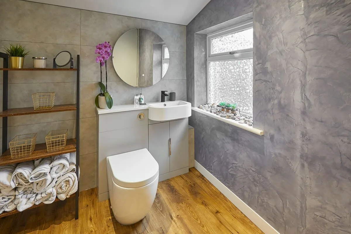 A bathroom with a sink, toilet, and window.