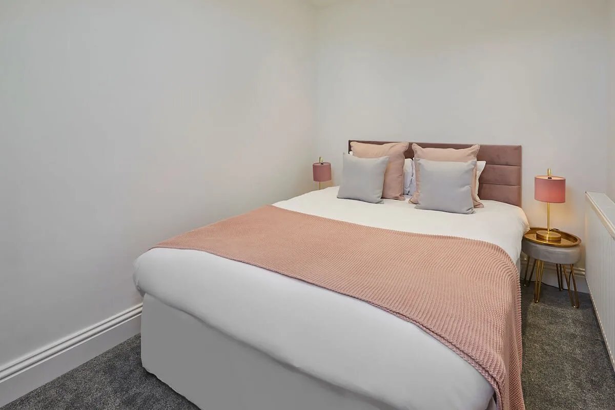 A bedroom with a neatly made bed and matching bedside lamps.