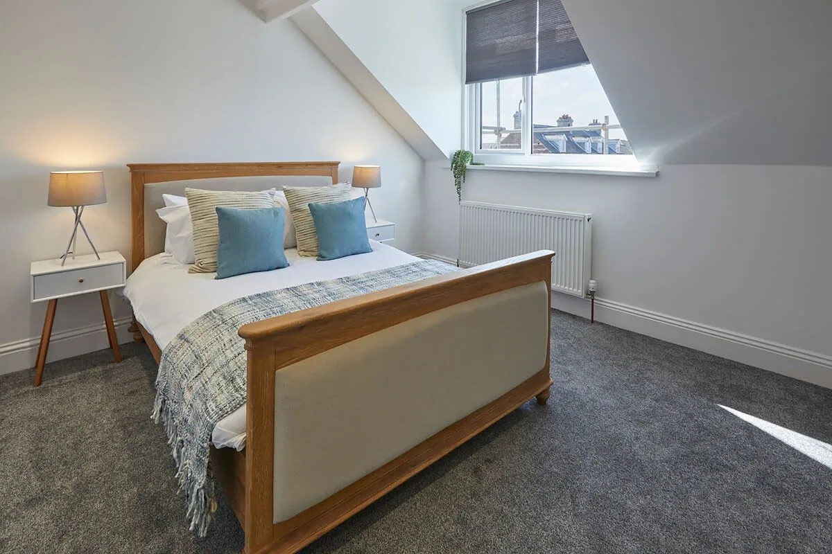 A bedroom with a wooden bed, bedside tables, and a window.