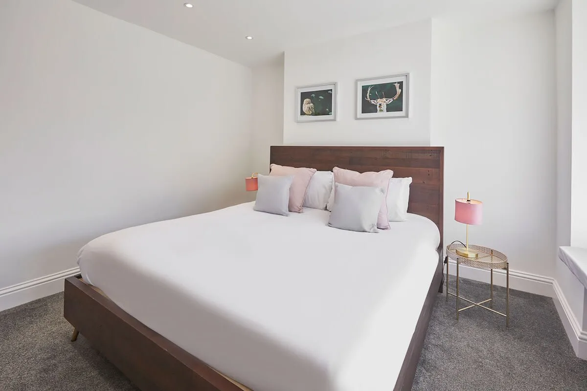 A bedroom with a bed and framed artwork above the headboard.