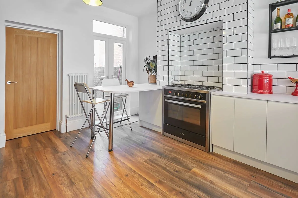 A bright kitchen with a dining table and built-in oven.