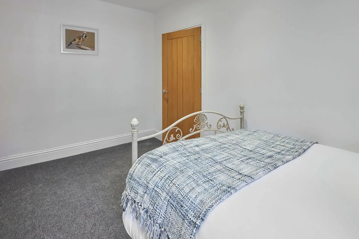 A bedroom with a bed, patterned blanket, and wooden door.