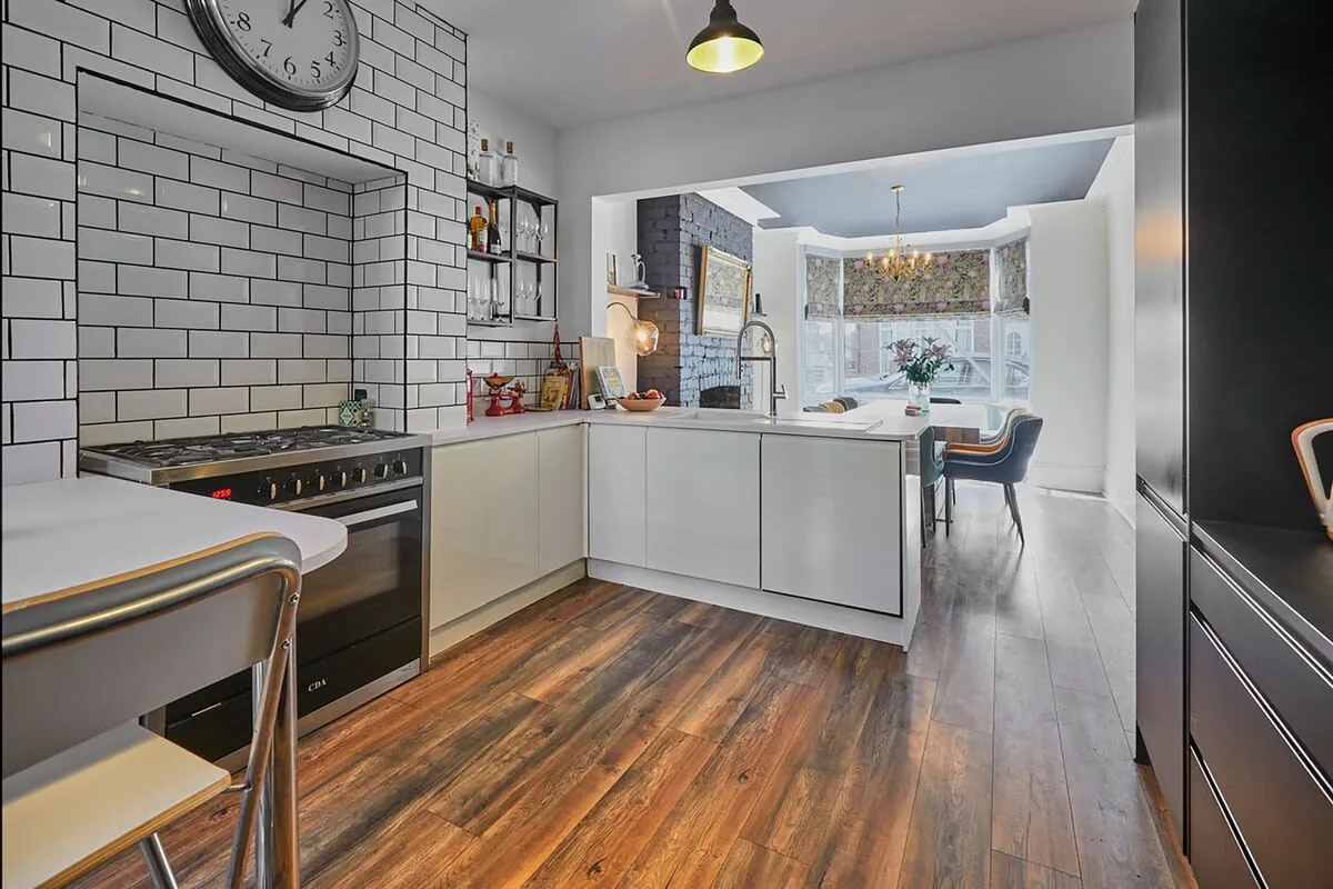 A modern kitchen with a tiled backsplash and an island opens into a dining area.