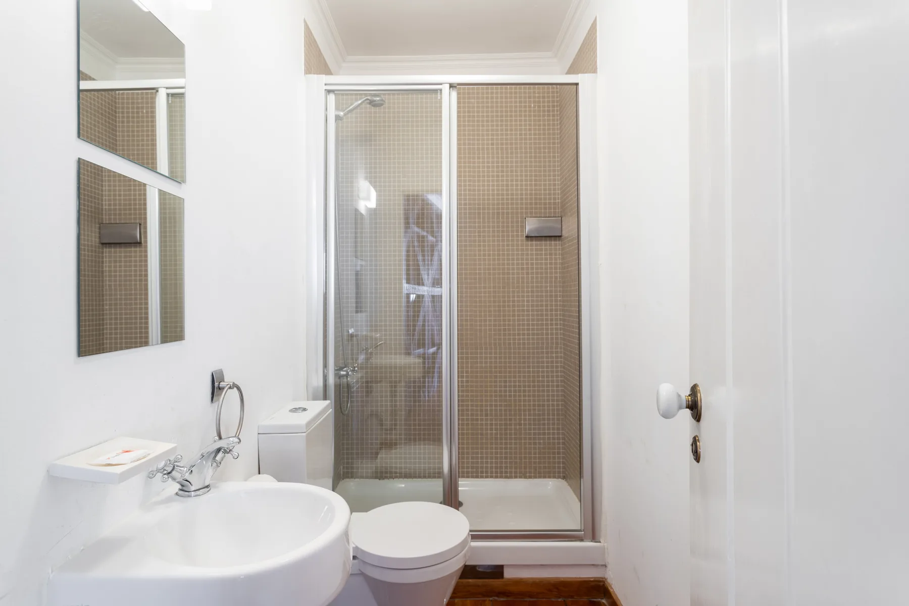 Baño con lavabo, inodoro y ducha con mampara de vidrio.