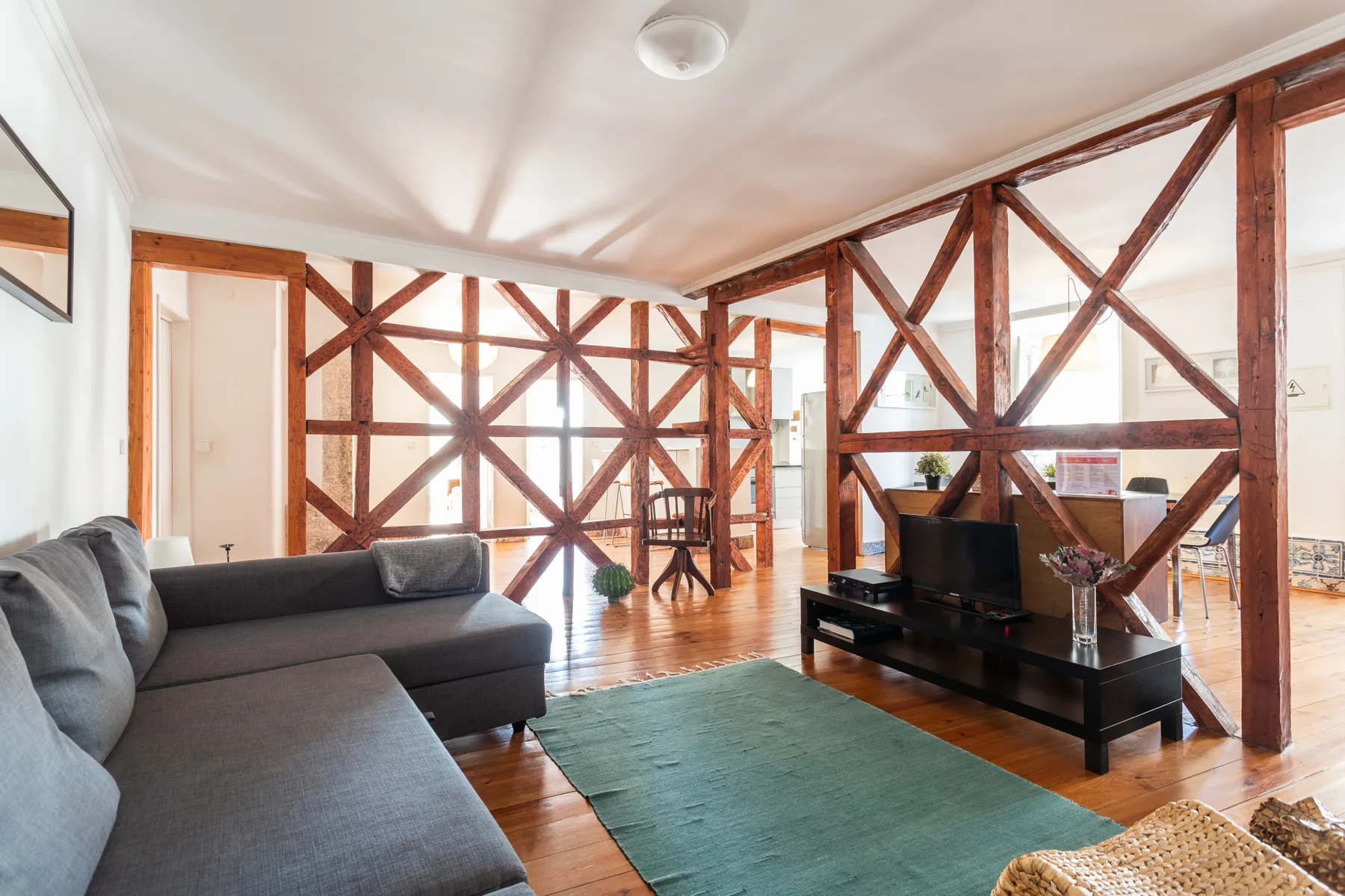 Sala de estar con asientos, un televisor y vigas de madera a la vista.