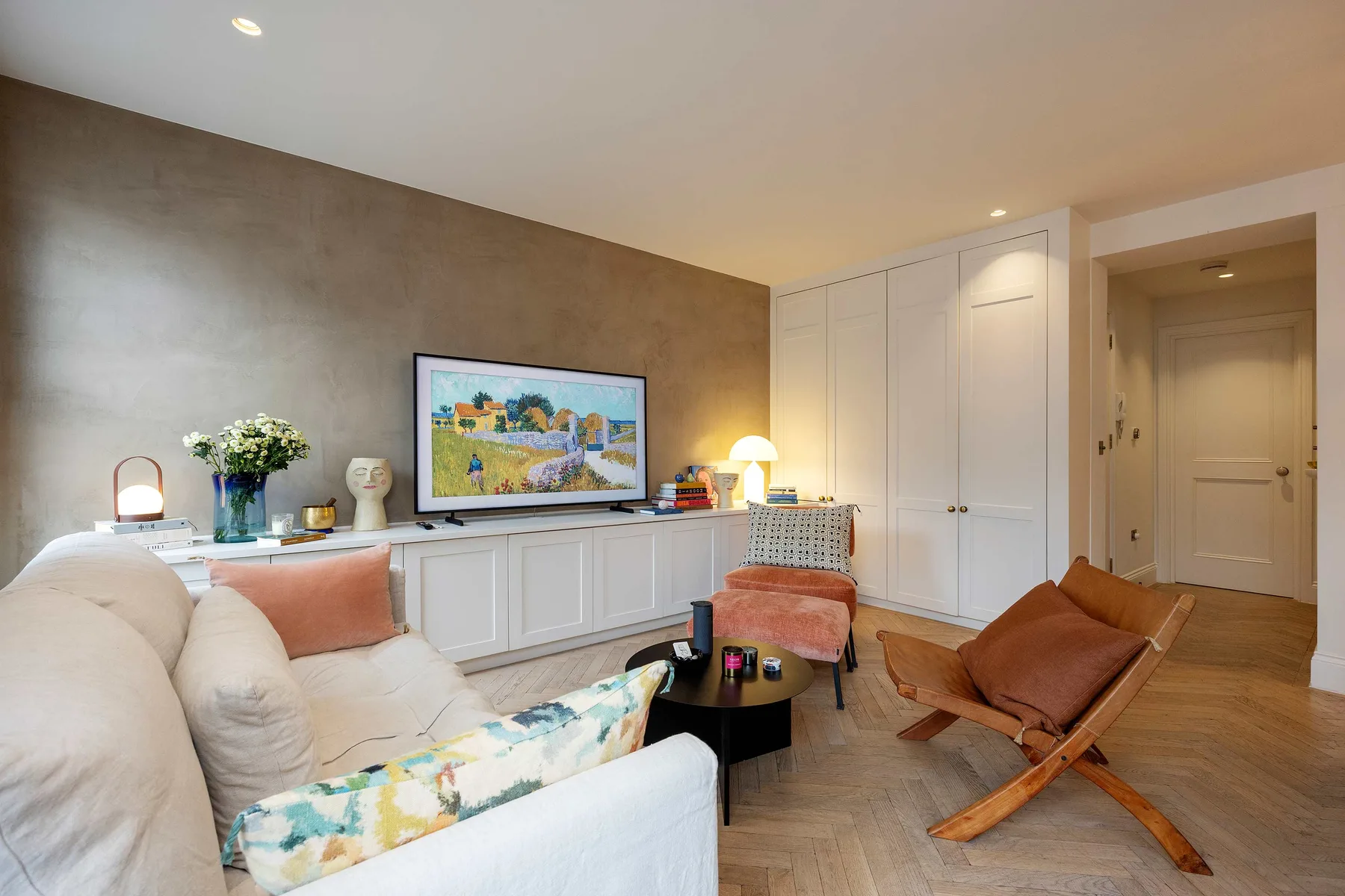A living room with seating, a television, and built-in cabinets.