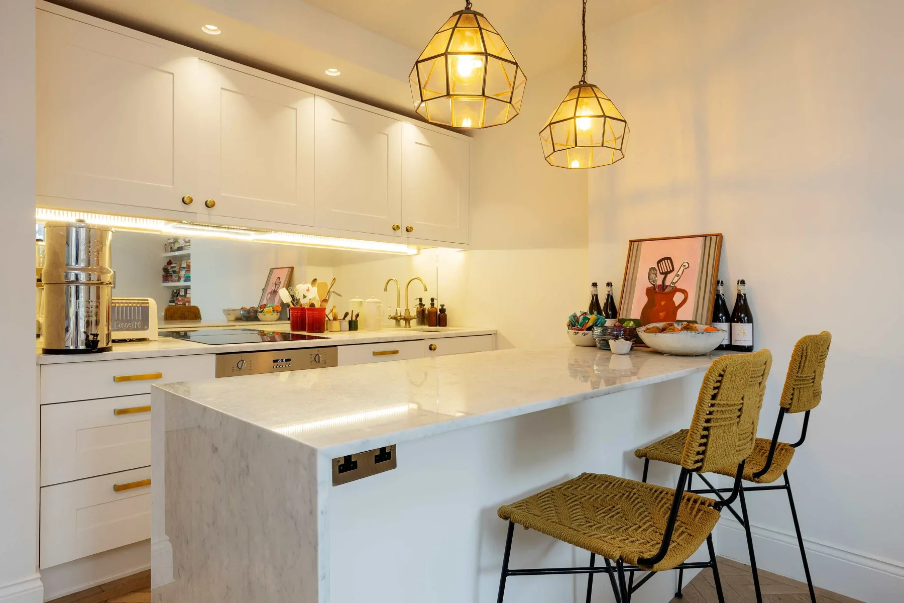 A bright kitchen with a white island and woven seating.