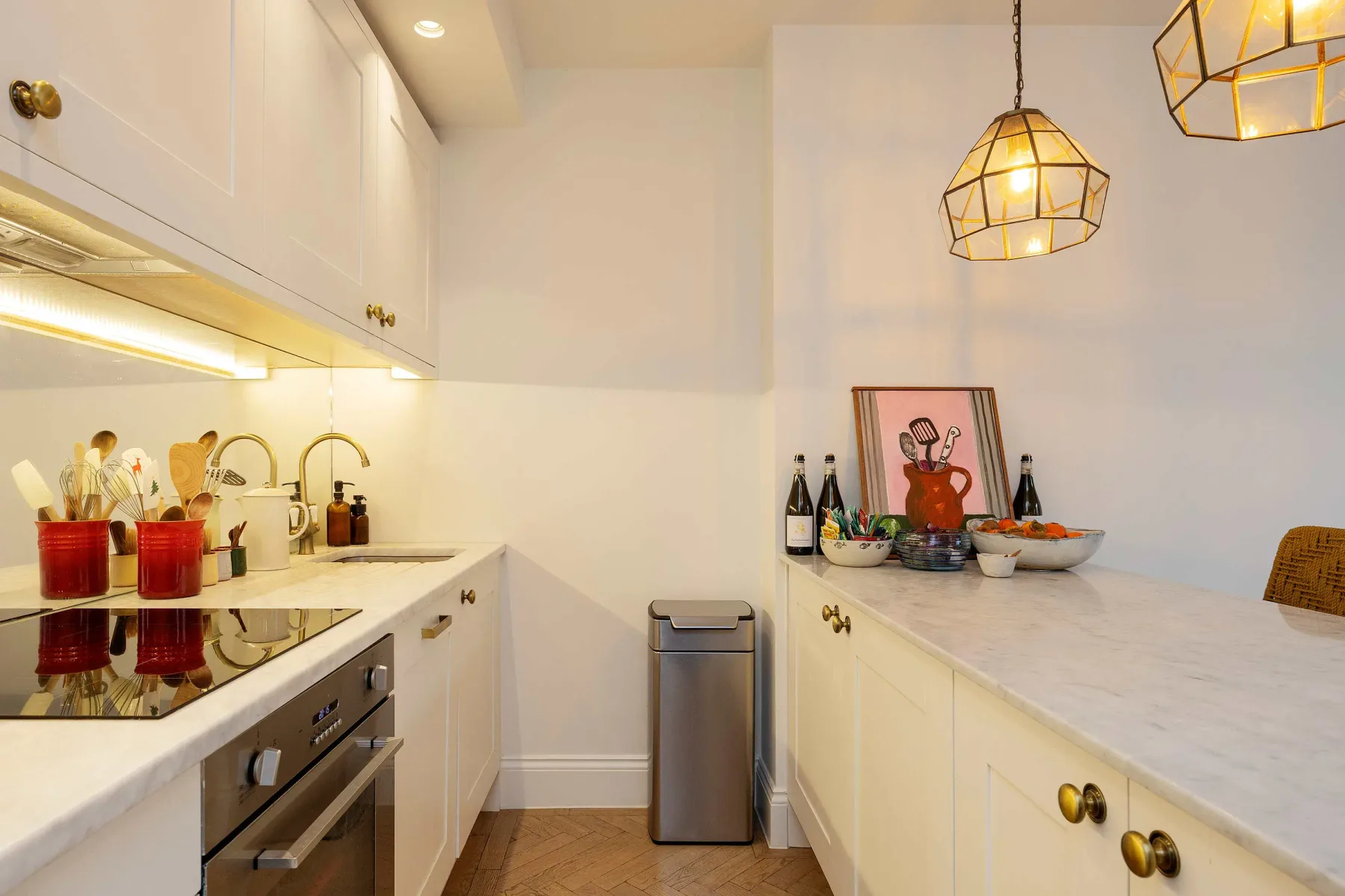 A bright kitchen with white cabinets, counters, and pendant lights.