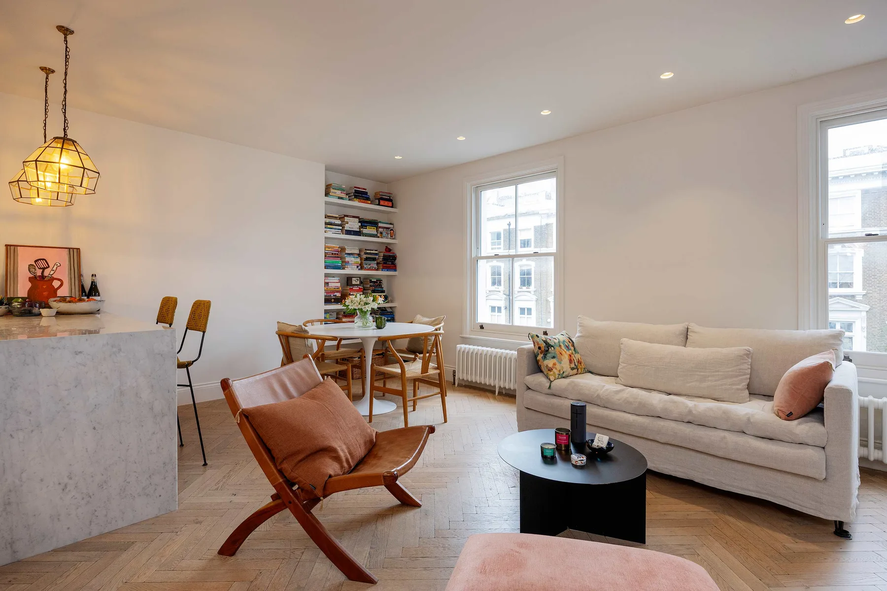 A bright living and dining area with a sofa, dining table, and bookshelves.