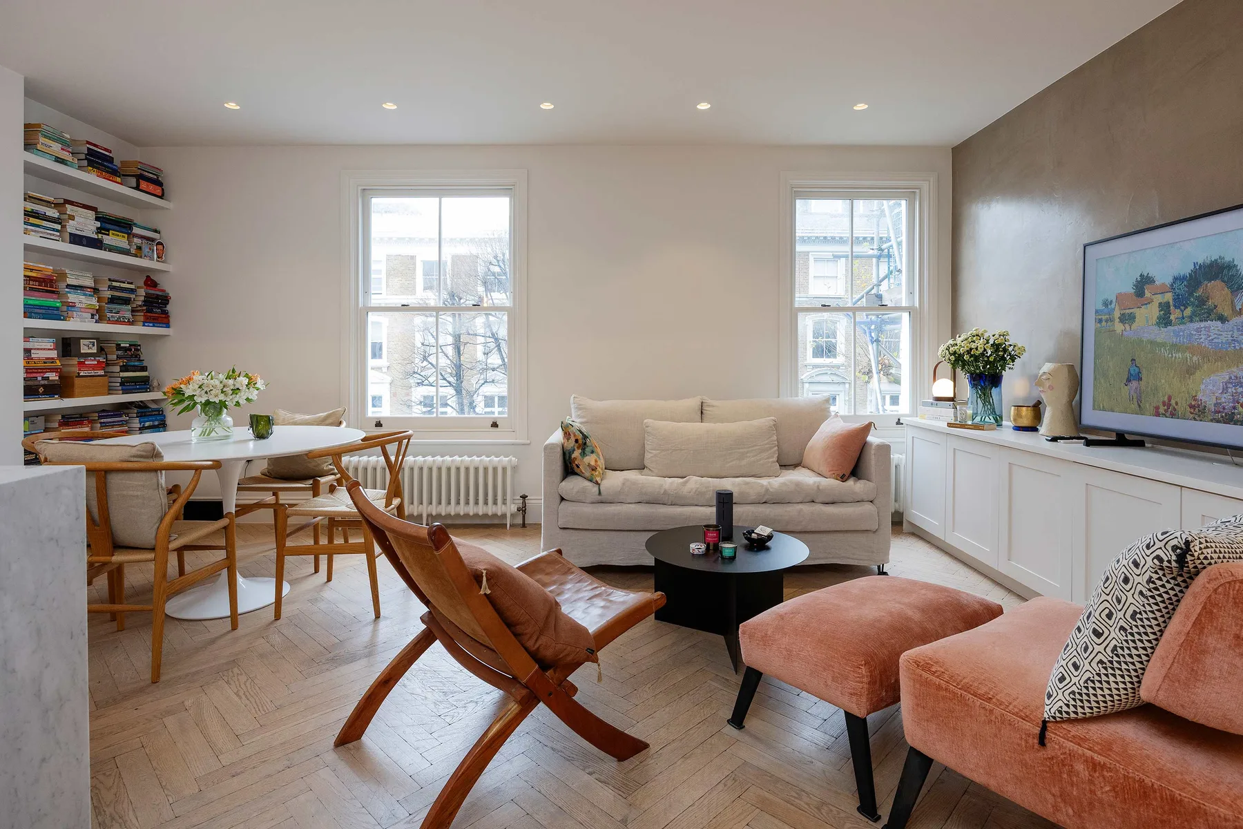 A bright living room with a sofa, lounge seating, and a dining table.