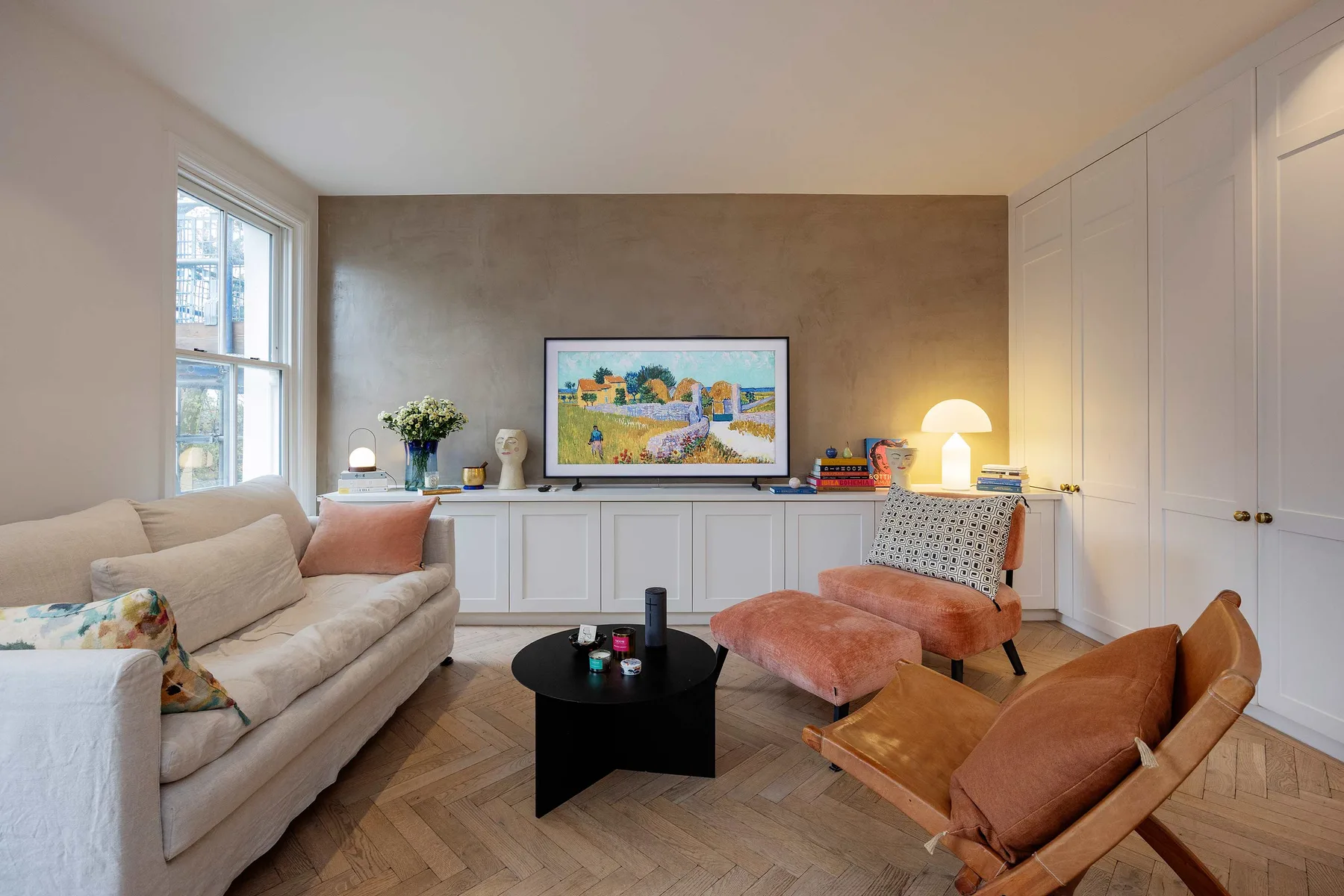 A bright living room with seating, a low table, and colorful artwork.
