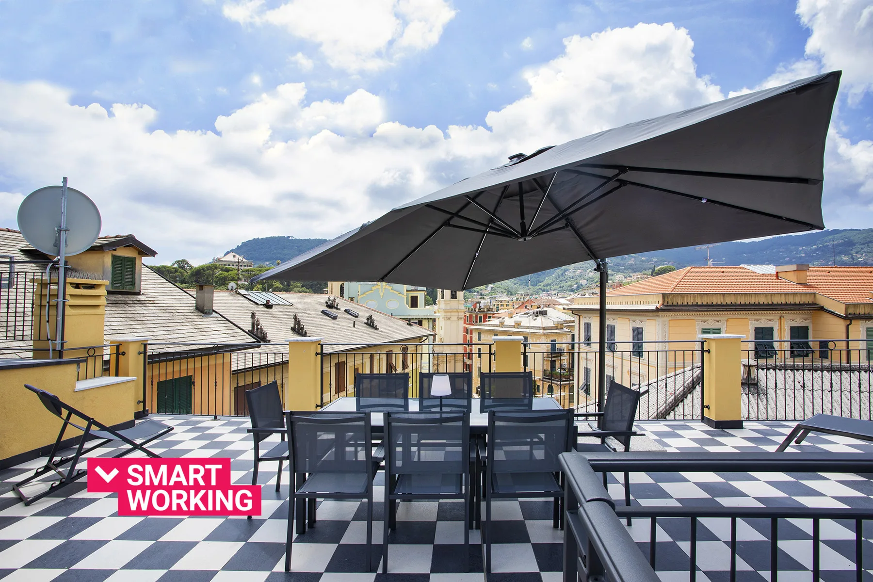 Una terraza en la azotea con asientos al aire libre bajo una sombrilla grande.