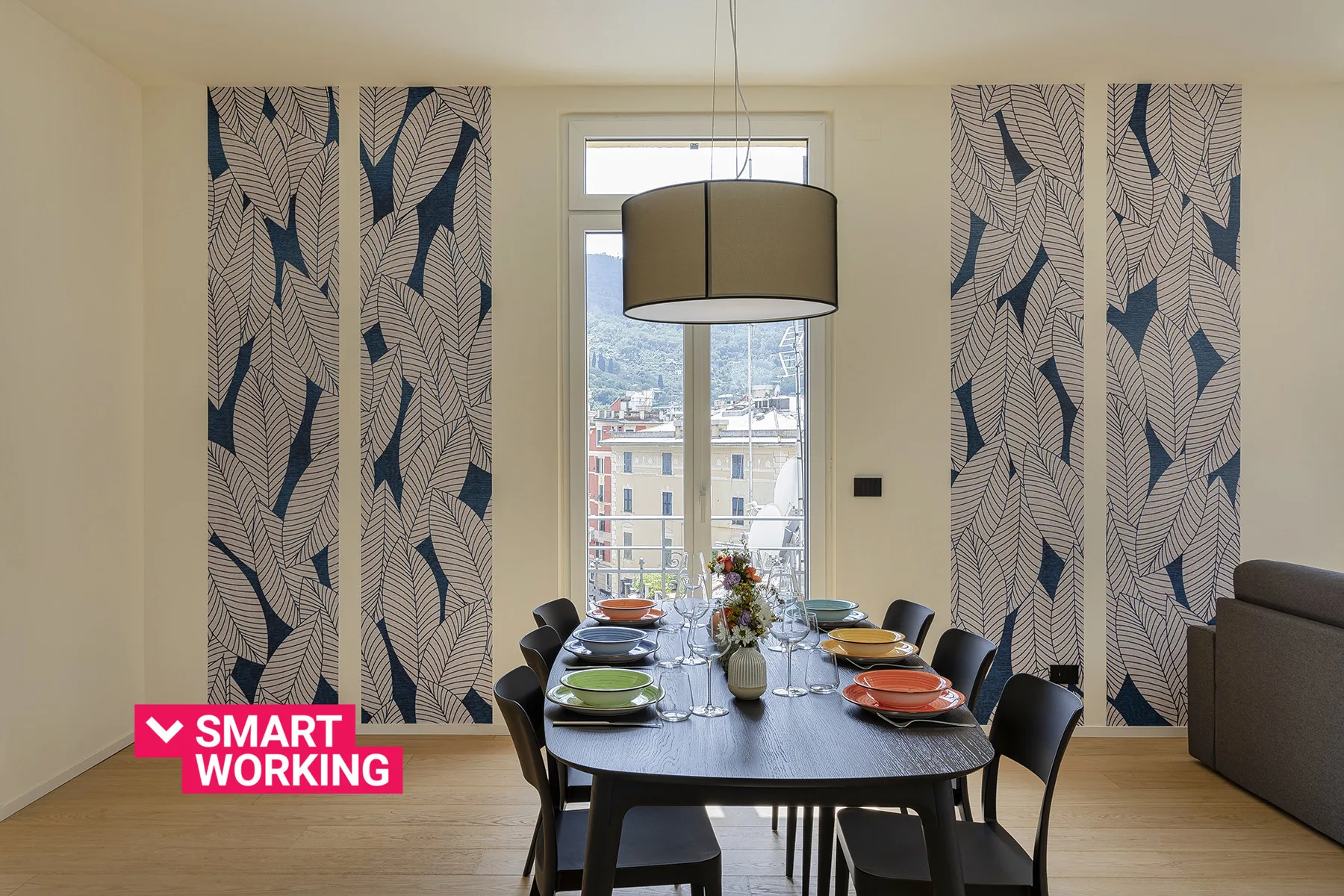 Un comedor con una mesa larga, sillas y cortinas estampadas.