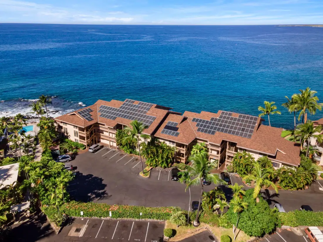 Vista aérea de un edificio costero con paneles solares junto al océano.