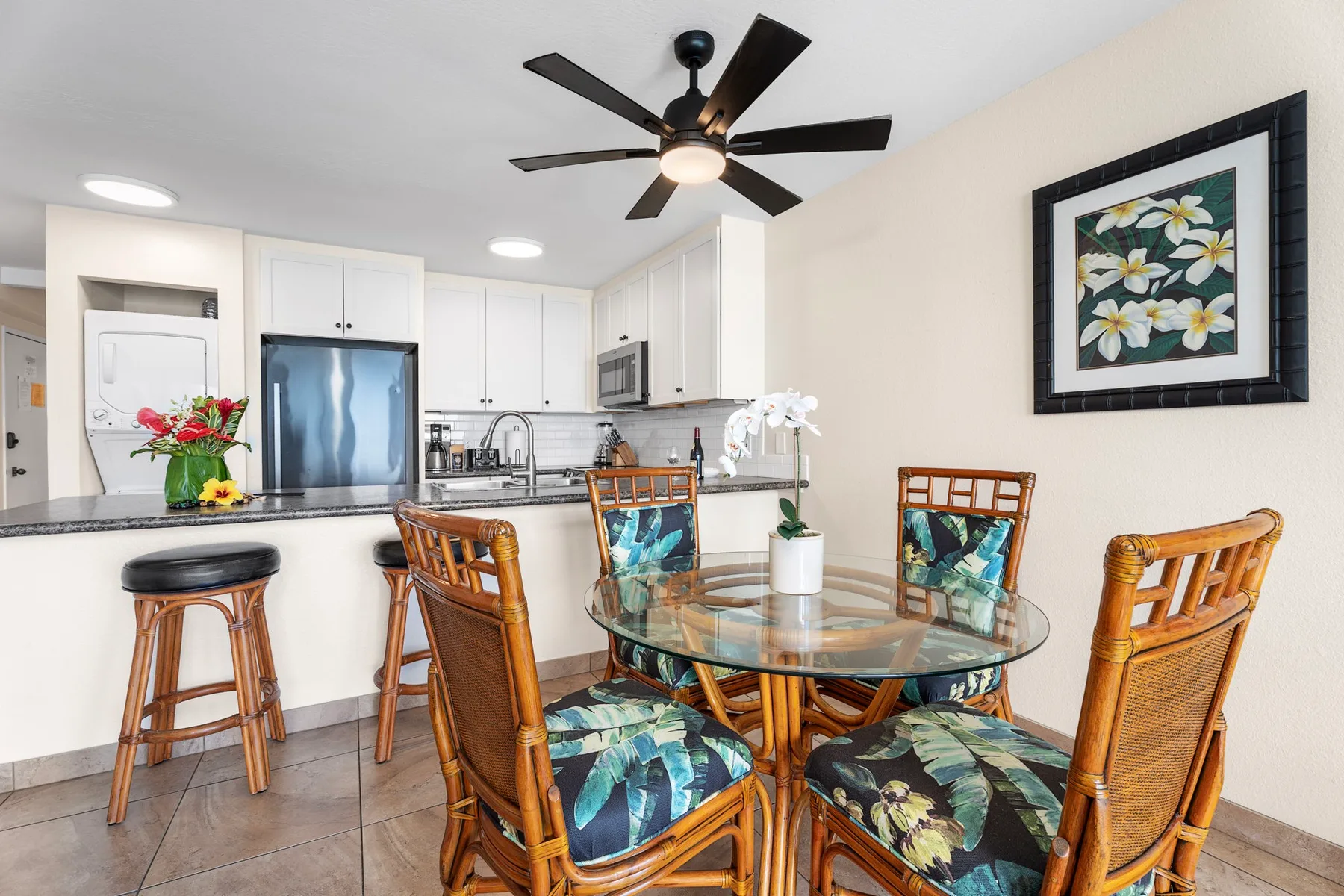 An open kitchen and dining area with a round glass table and wicker seating.