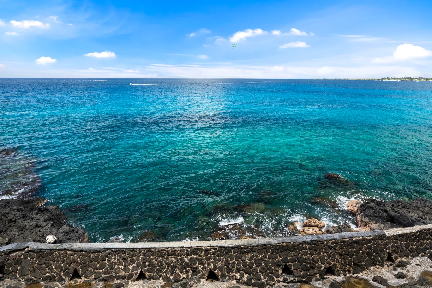 El mar azul claro llega a una costa rocosa bajo un cielo despejado.