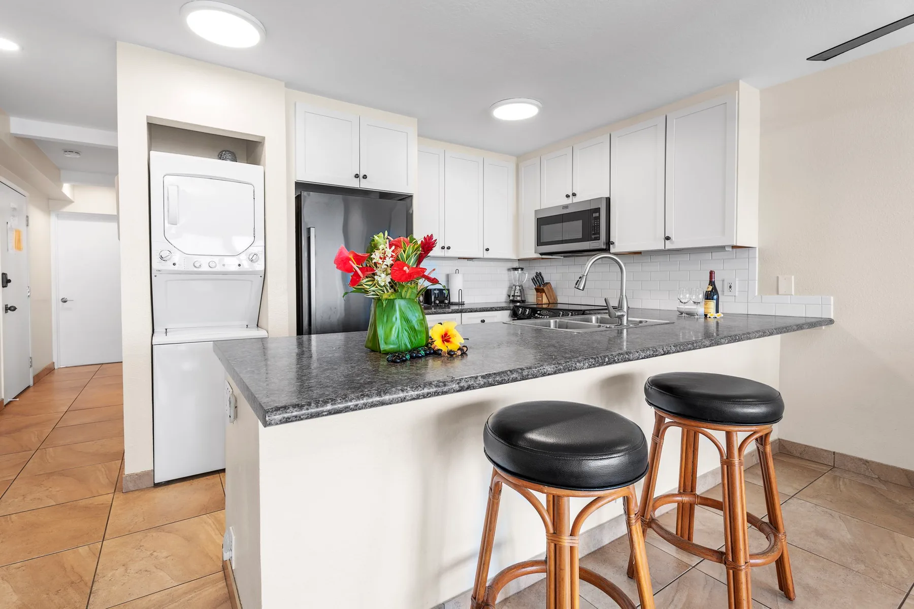 Una cocina luminosa con una isla grande, asientos de barra y gabinetes blancos.