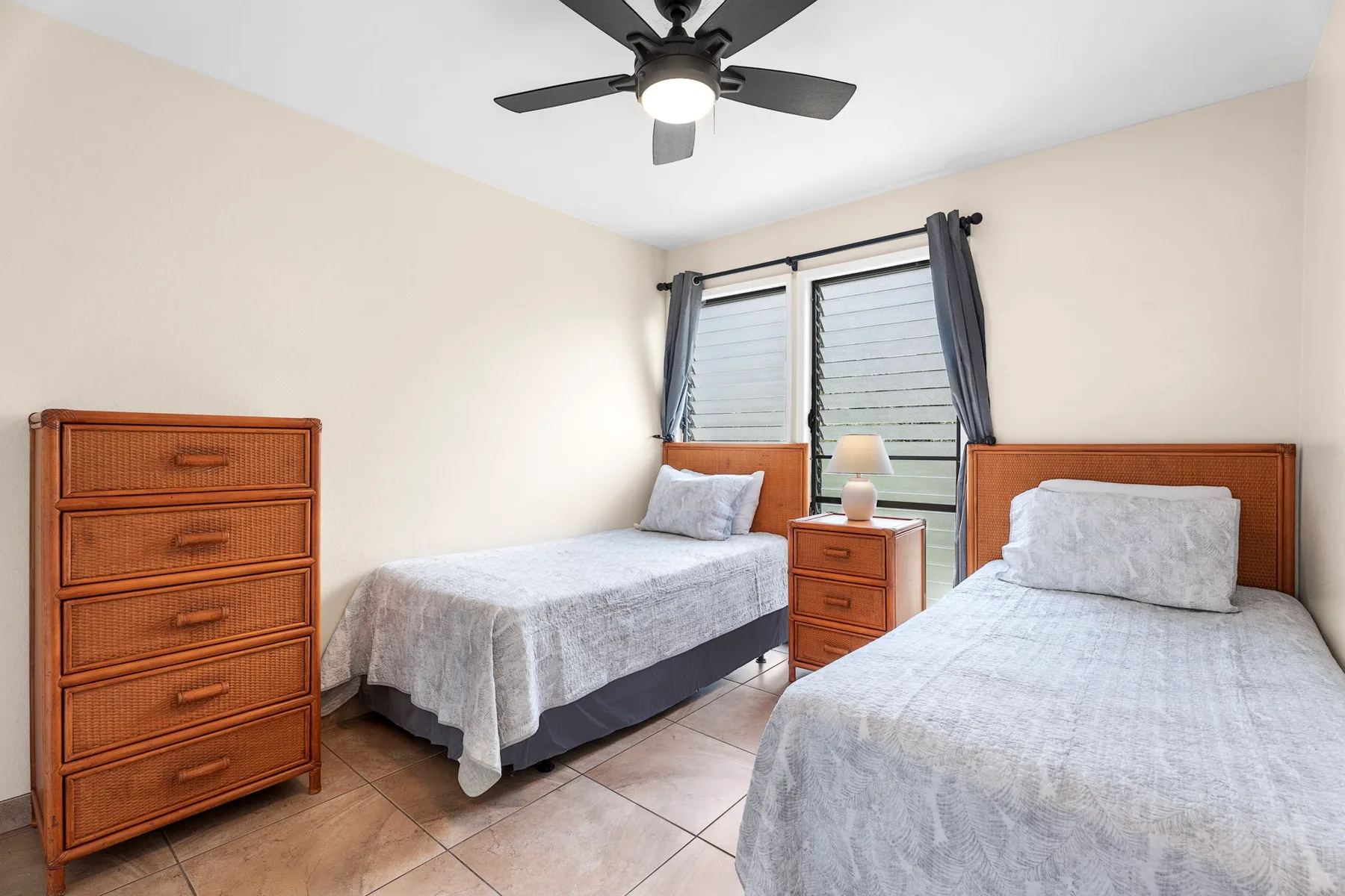 Un dormitorio con dos camas individuales, cómodas de madera y una ventana con cortinas.