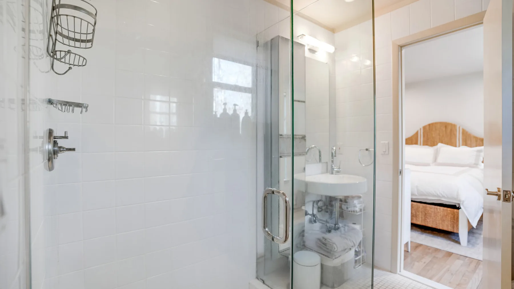 Un baño con azulejos, una ducha de vidrio y un lavabo junto a la puerta.