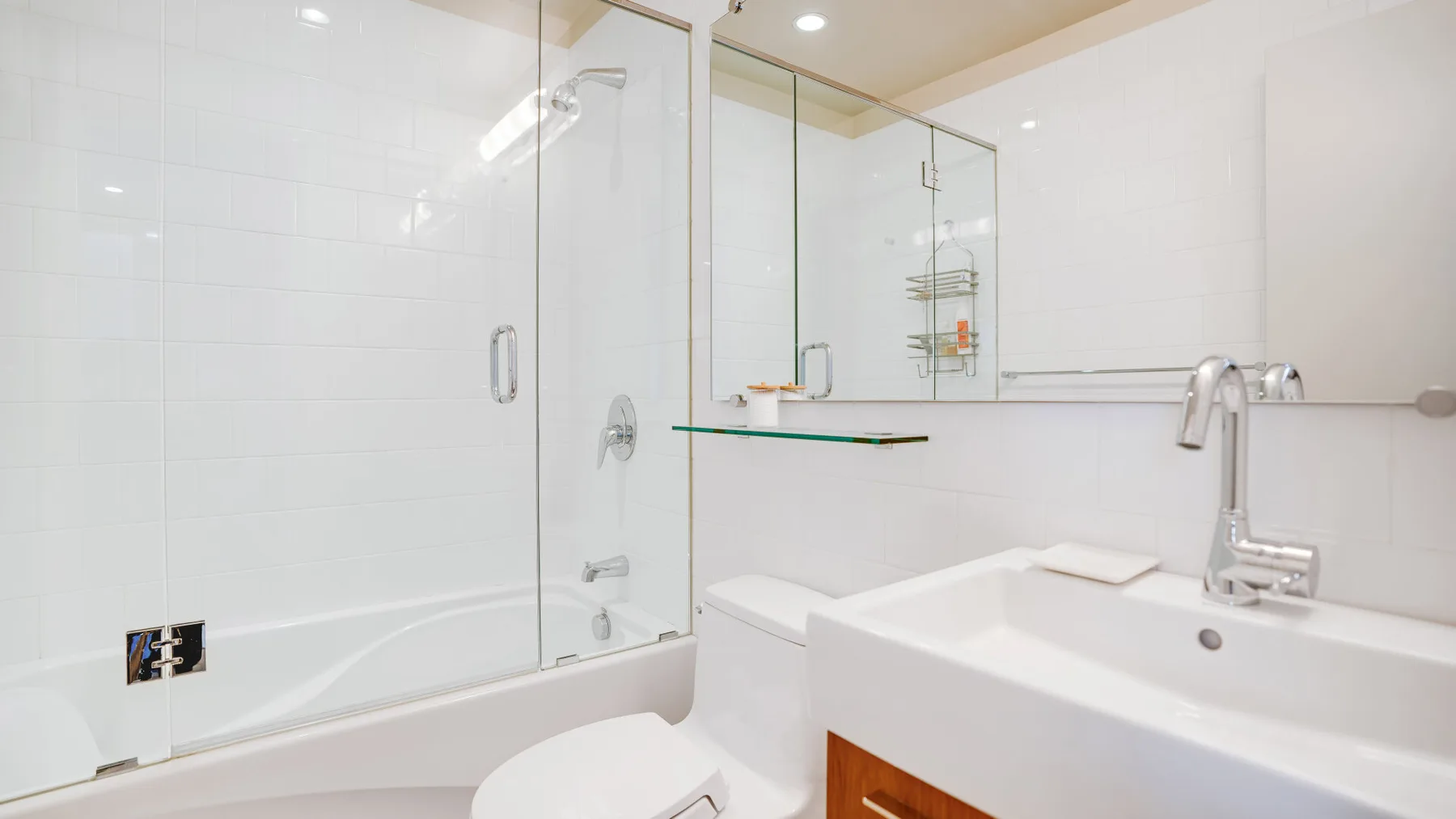Un baño blanco y luminoso con una ducha de vidrio y una bañera grande.
