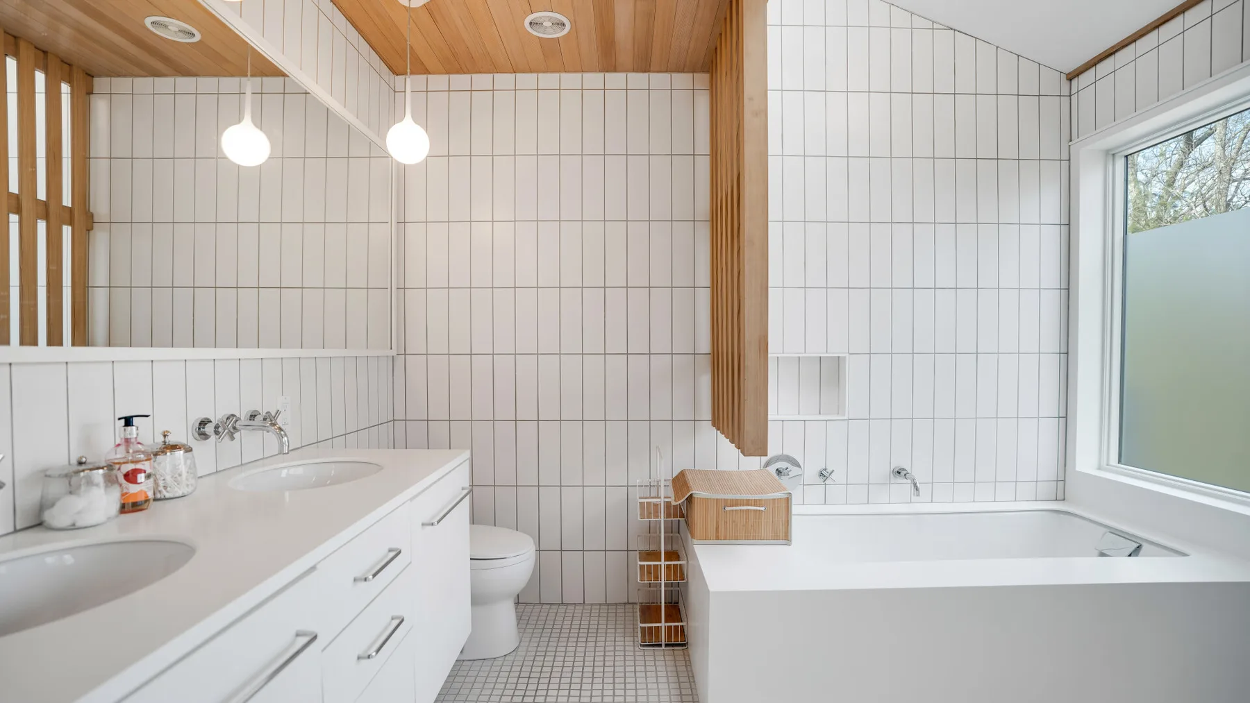 Un baño revestido de azulejos con bañera, lavabo y techo de madera cálida.
