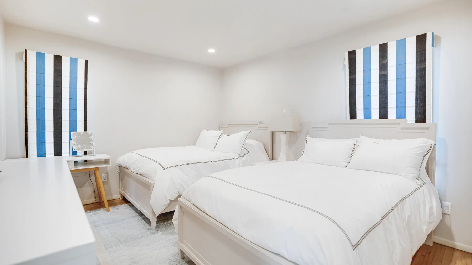 Un dormitorio luminoso con dos camas vestidas con ropa de cama blanca.