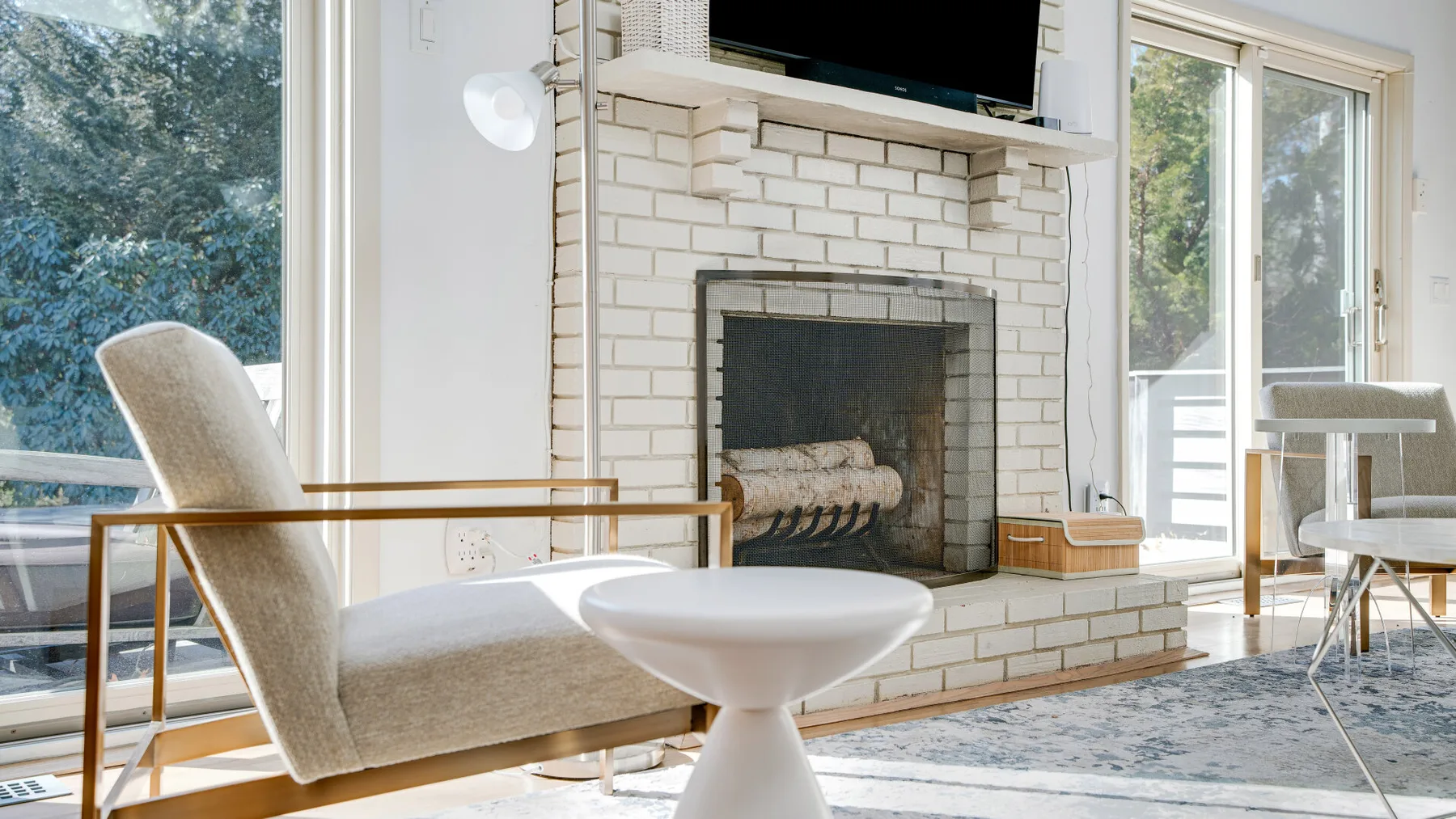Una sala luminosa con chimenea, asientos y ventanales.