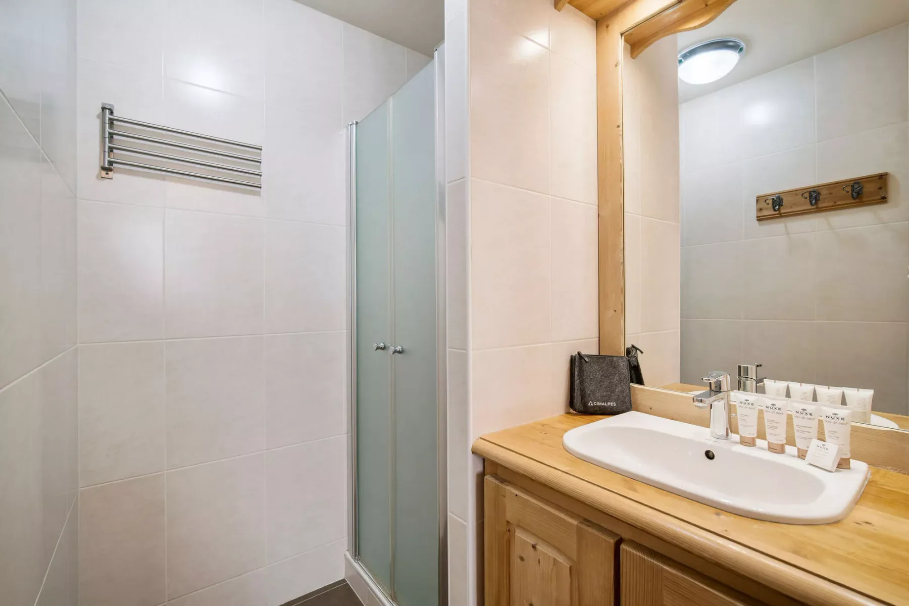 Un baño con azulejos, una ducha de vidrio y un mueble de madera con lavabo.