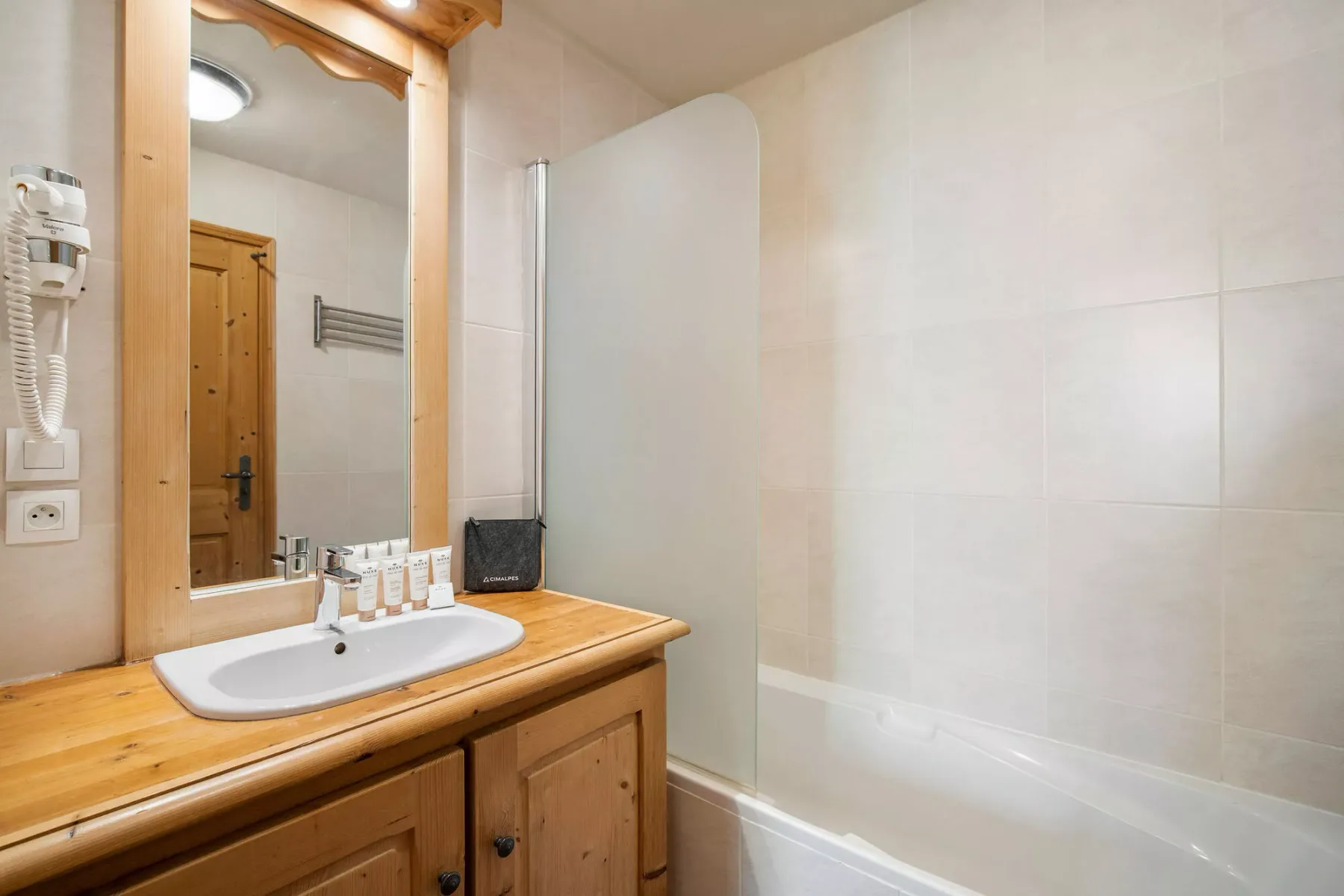 Un baño con un mueble de madera, lavabo y bañera.