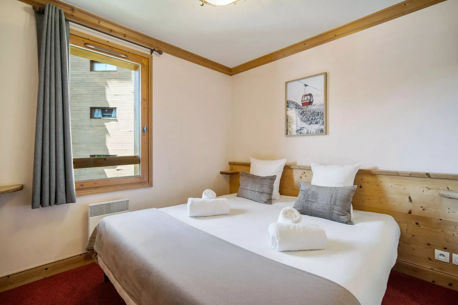 Un dormitorio con una cama bien tendida y una ventana al lado.
