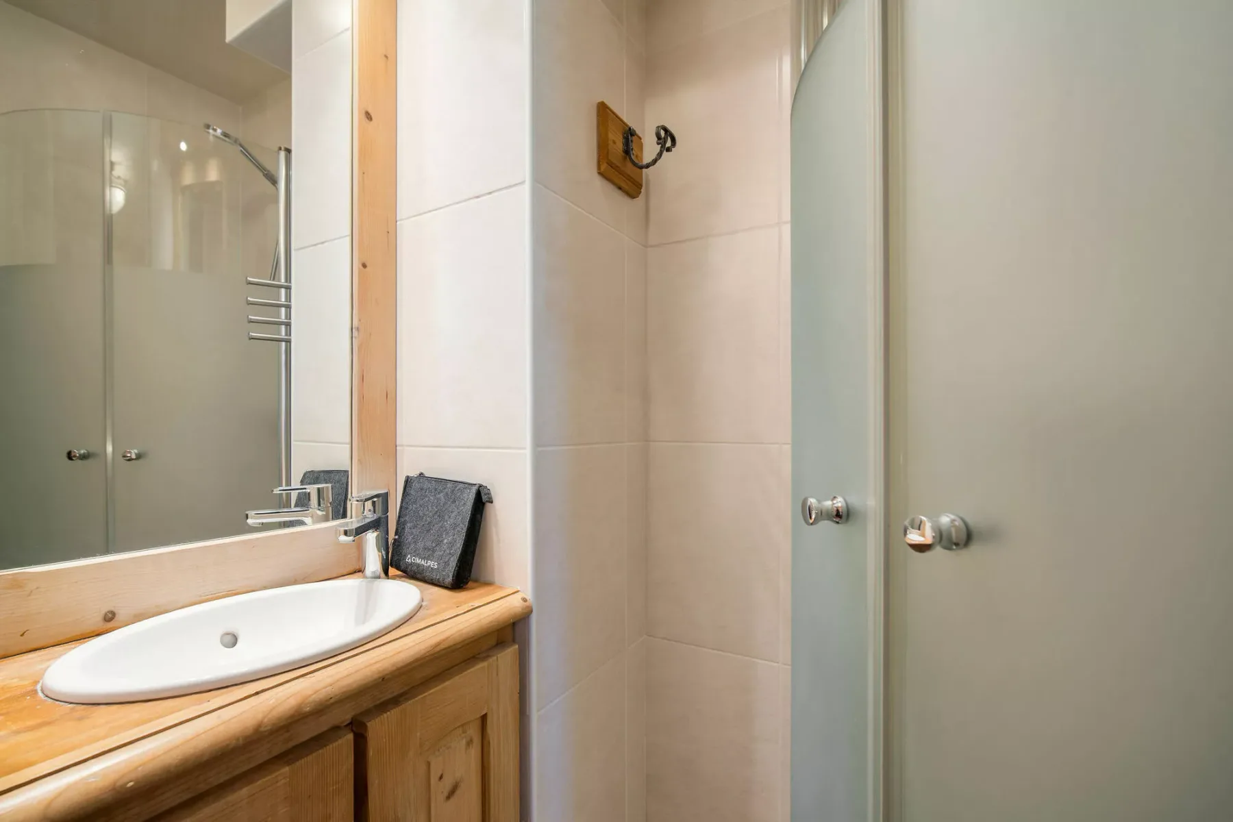 Un baño con lavabo, mueble de madera y mampara de ducha de vidrio.