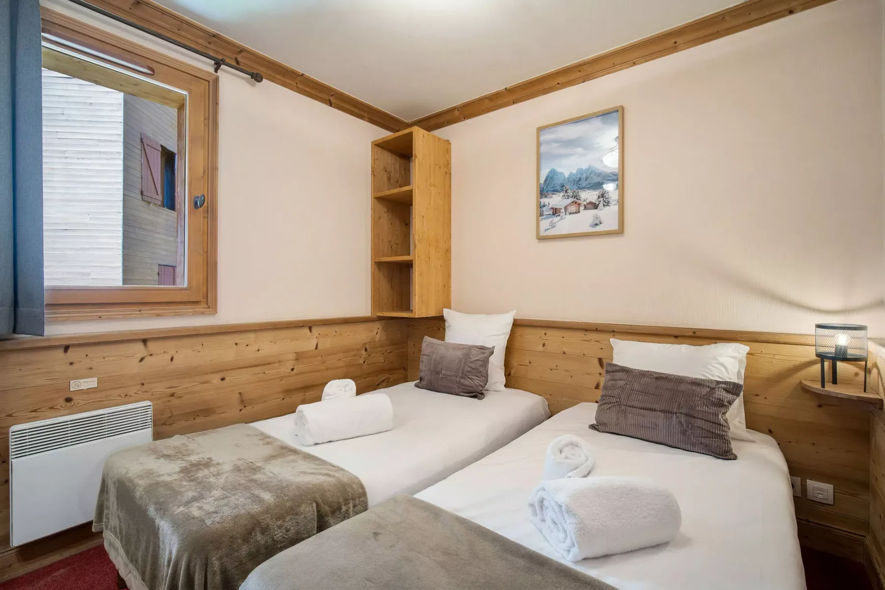Un dormitorio con dos camas, toallas dobladas y paneles de madera.