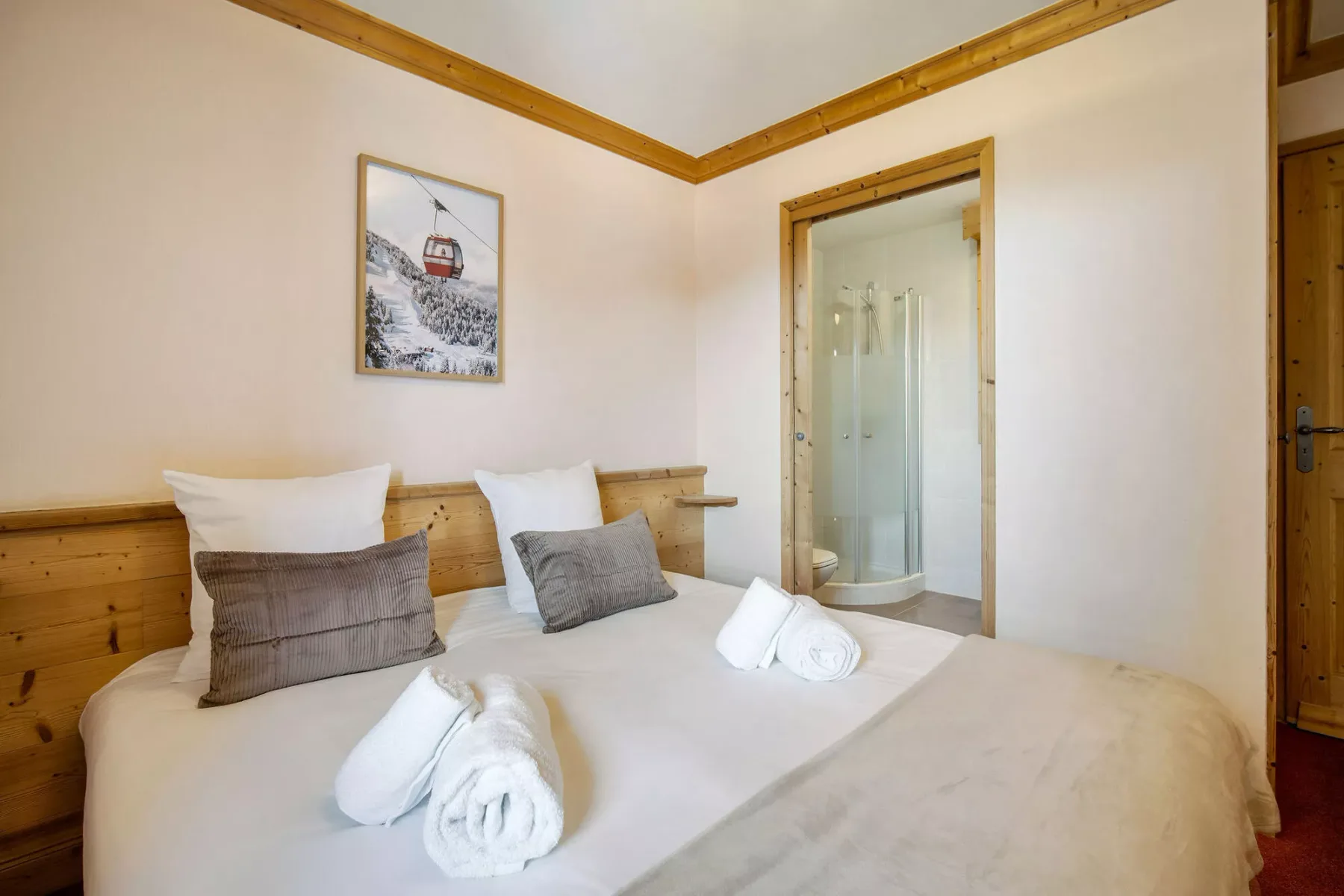 Un dormitorio con una cama bien tendida y una puerta abierta a una ducha.